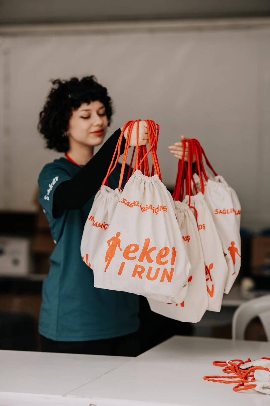 A woman holding printed event bags with orange drawstrings