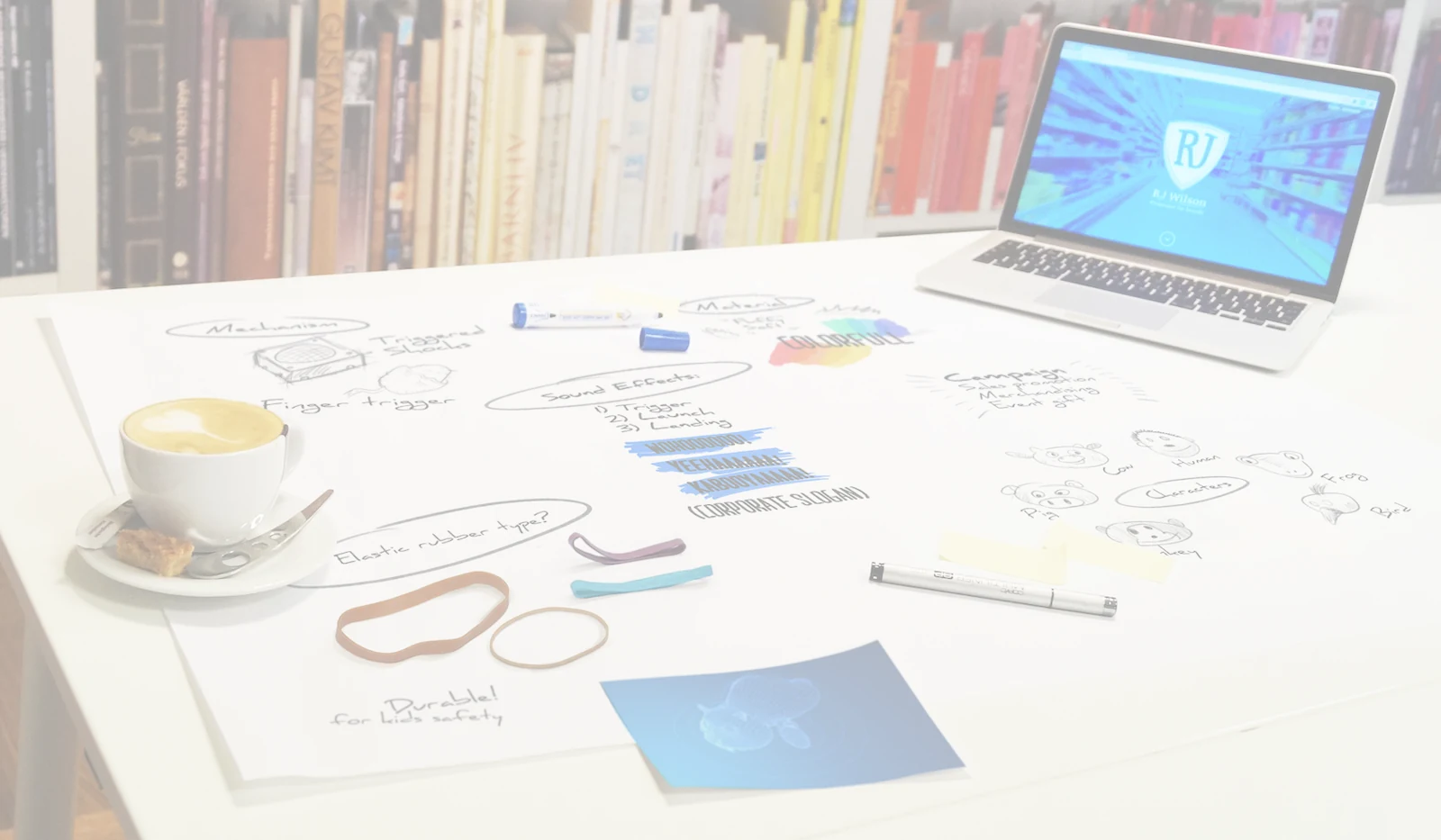 Tafel met ontwerpschetsen, materiaalvoorbeelden, een kop koffie en een laptop