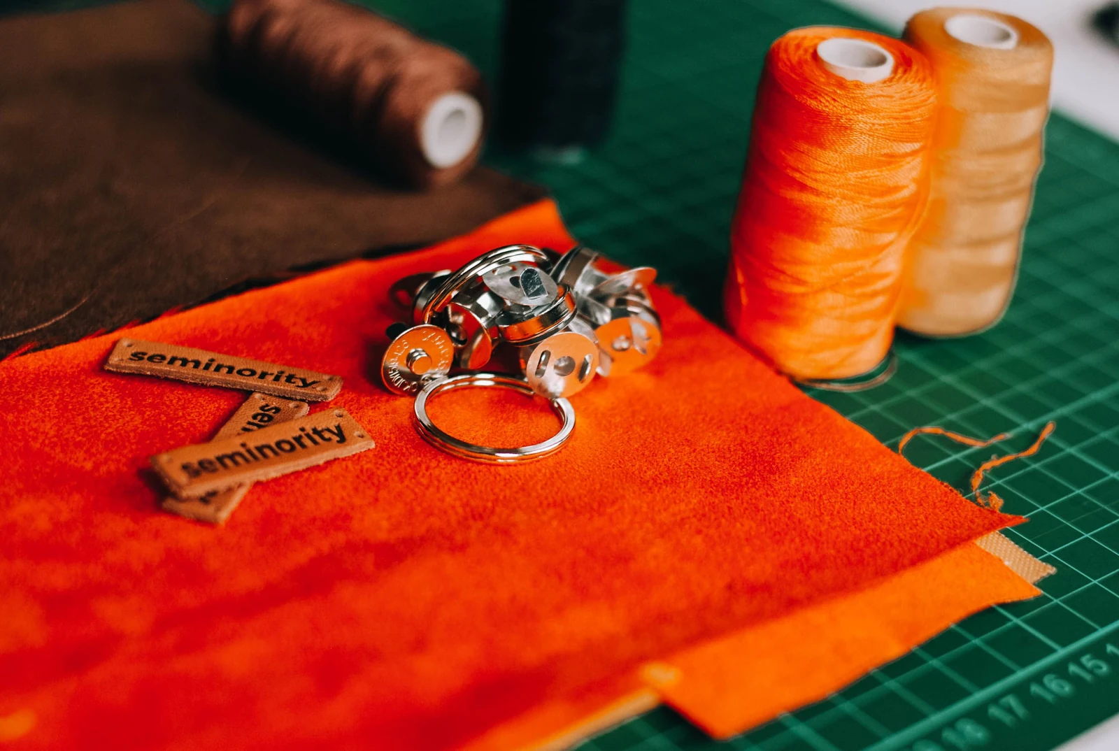 Oranje stof, kleurrijk garen en metalen onderdelen op een snijmat